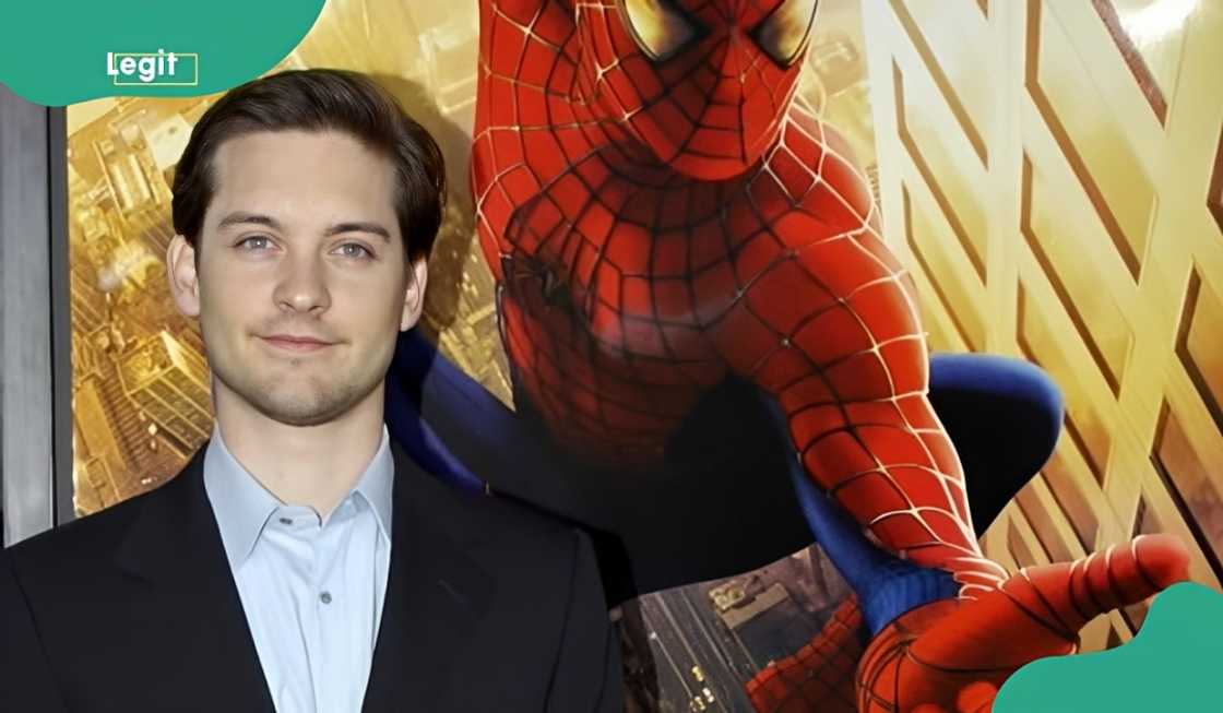 Tobey Maguire poses next to a Spiderman poster