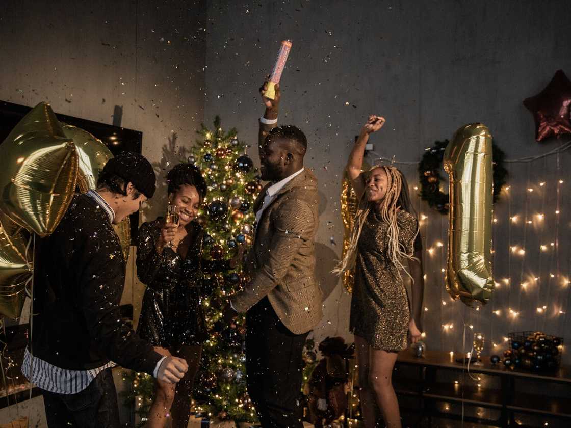 A group of people celebrate indoors with confetti and raised hands.