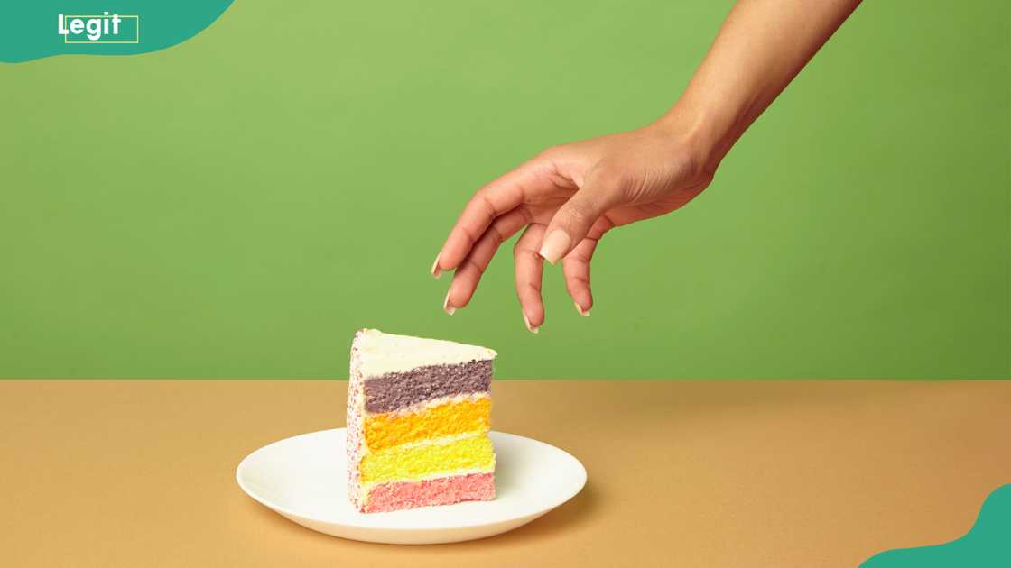 A woman's hand reaching for a slice of cake on a table