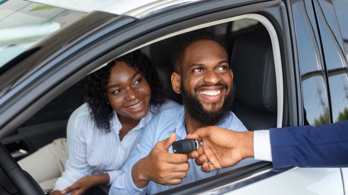New owners of a vehicle pictured receiving a car key. New owners of a vehicle pictured receiving a car key.