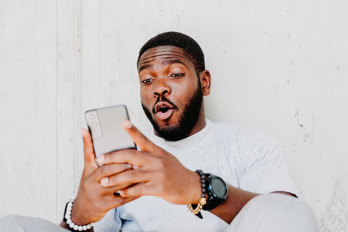 A man with a surprised facial expression holding a smartphone in his hands, chatting