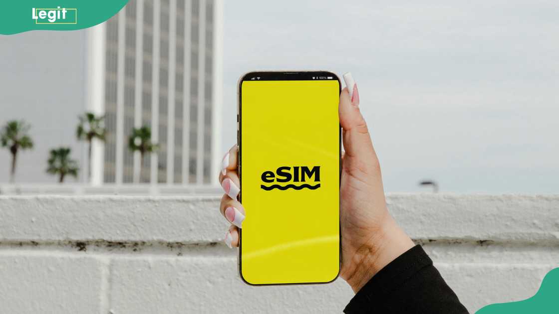 A hand holding a smart phone with an eSIM logo