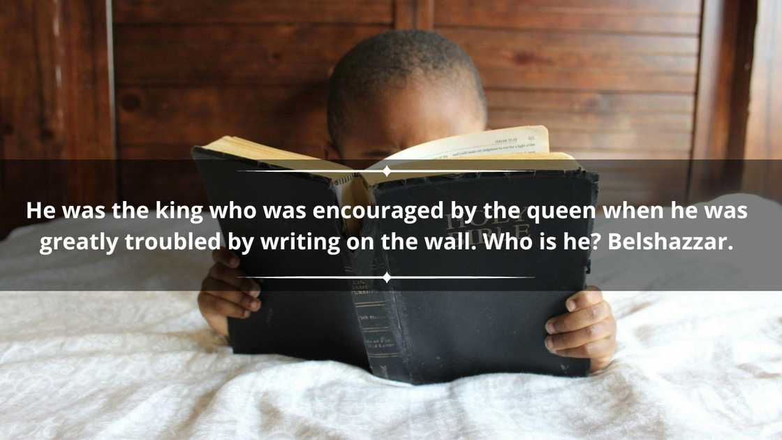 A little boy is reading an old Bible in bed