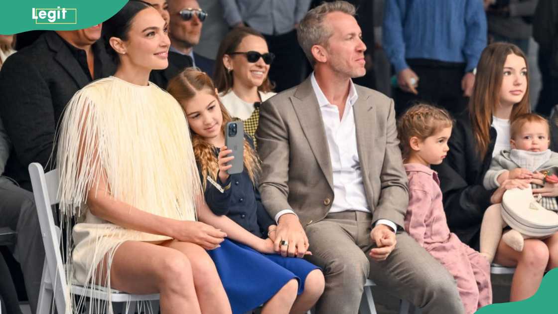 A woman in a fringed dress and a man in a gray suit sit front row with three children beside them.