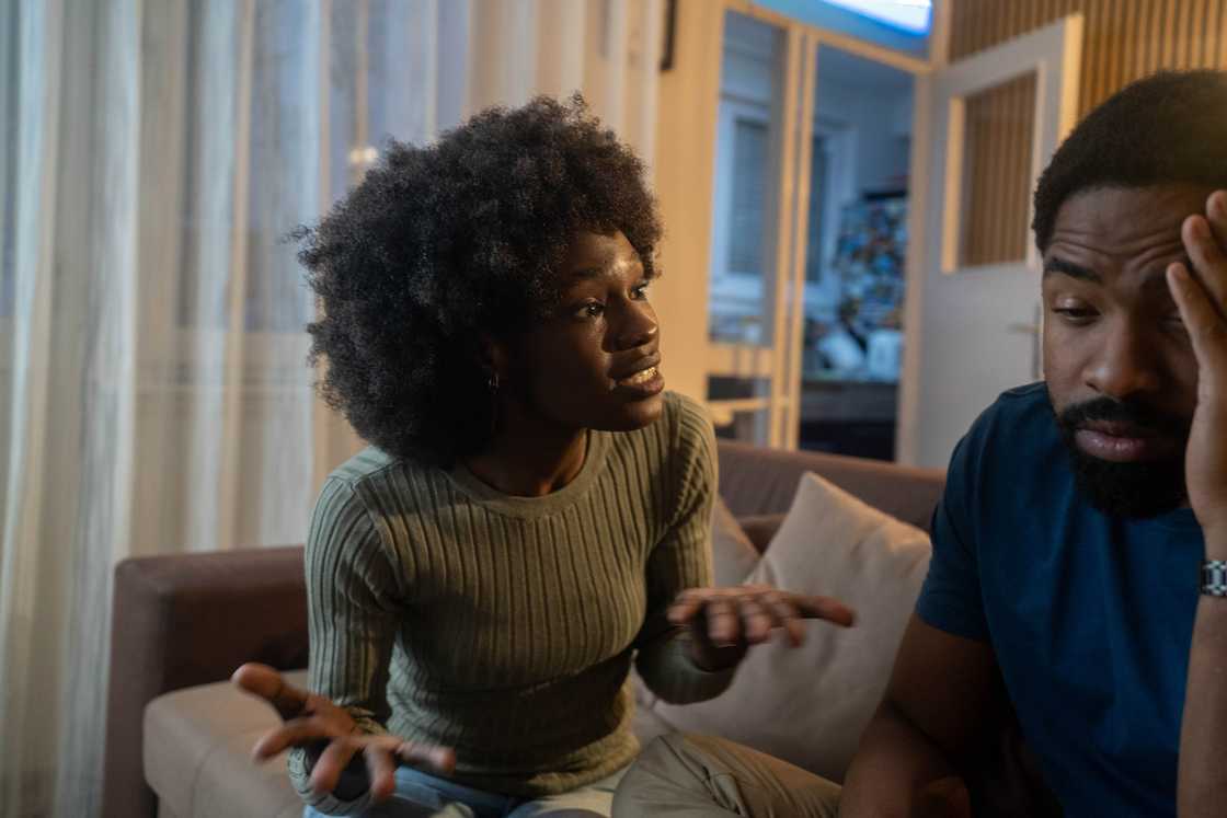 A couple sitting on sofa arguing