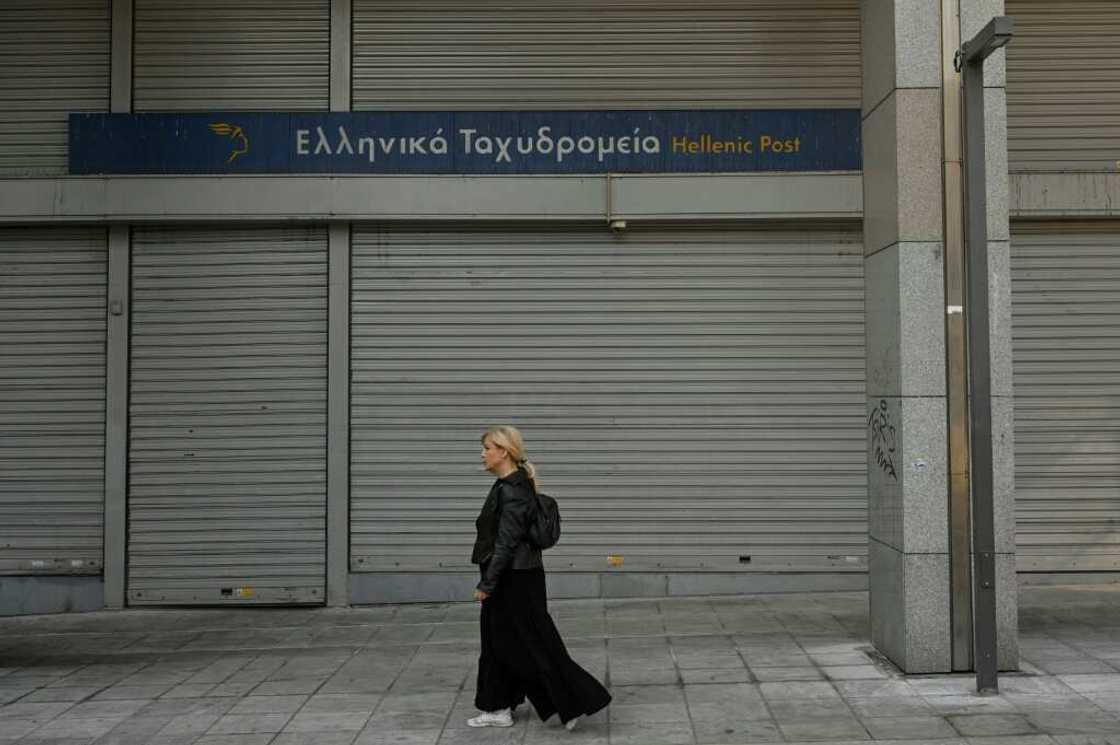 A woman walks past a closed post office during a 24-hour strike in Athens A woman walks past a closed post office during a 24-hour strike in Athens