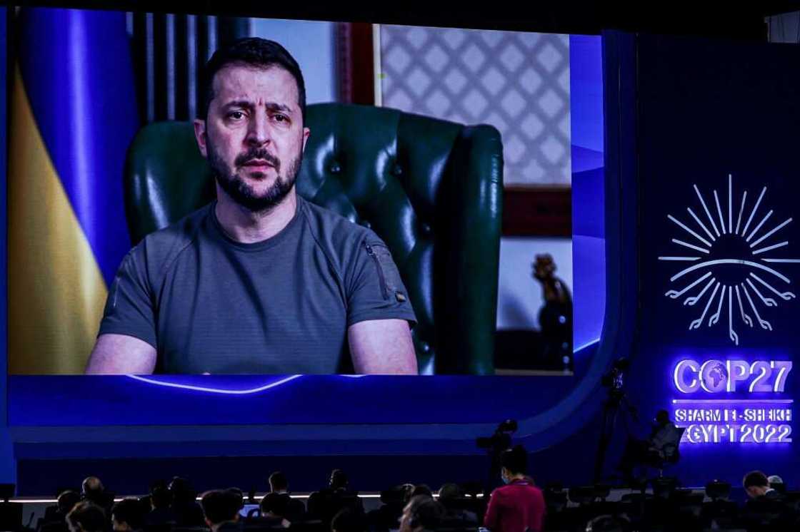 Ukrainian President Volodymyr Zelensky, seen delivering a COP 27 speech, has led the way since the conflict began with his olive t-shirts and other military-toned outfits