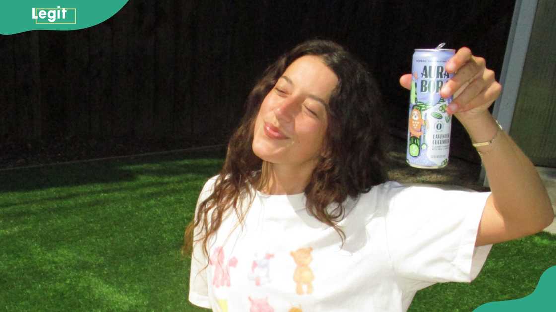 A lady enjoys a moment as she holds an Aura Bora drink A lady enjoys a moment as she holds an Aura Bora drink