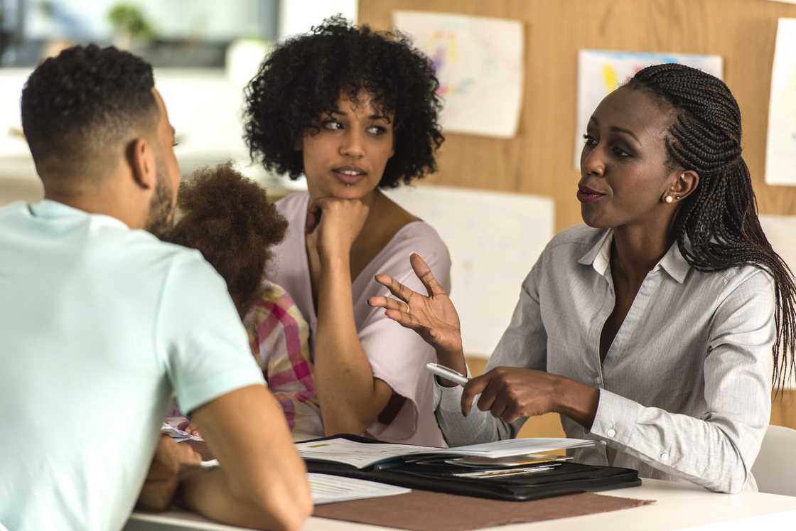 Headteacher, teacher, and parent in discussion inside an office.