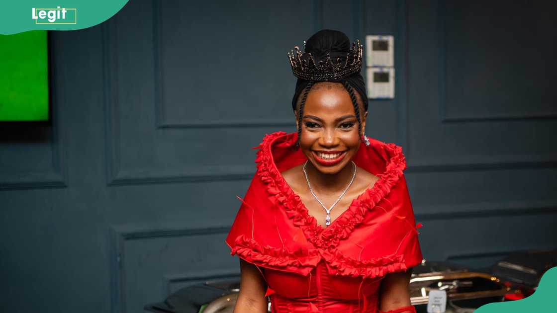 Taaooma in front of a background muted gray-blue wall with molding details Taaooma in front of a background muted gray-blue wall with molding details