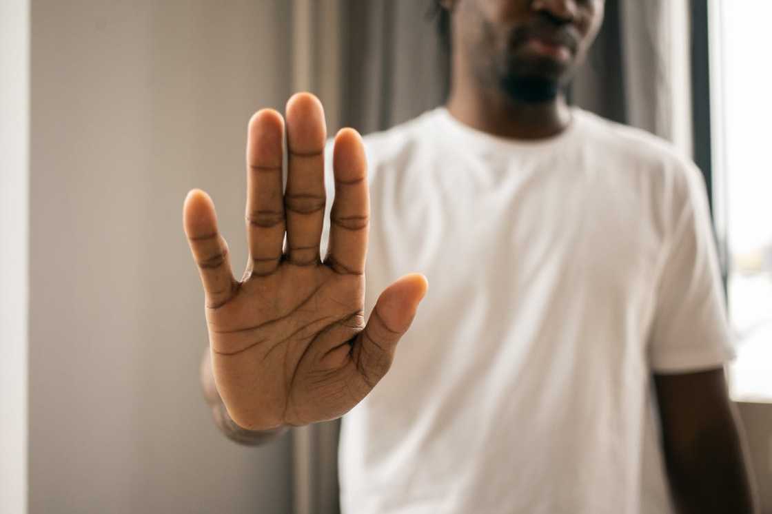 A person holds up an open hand in a stop gesture.