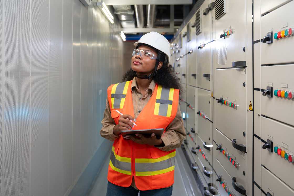 A woman engineer stands in an electrical hallway