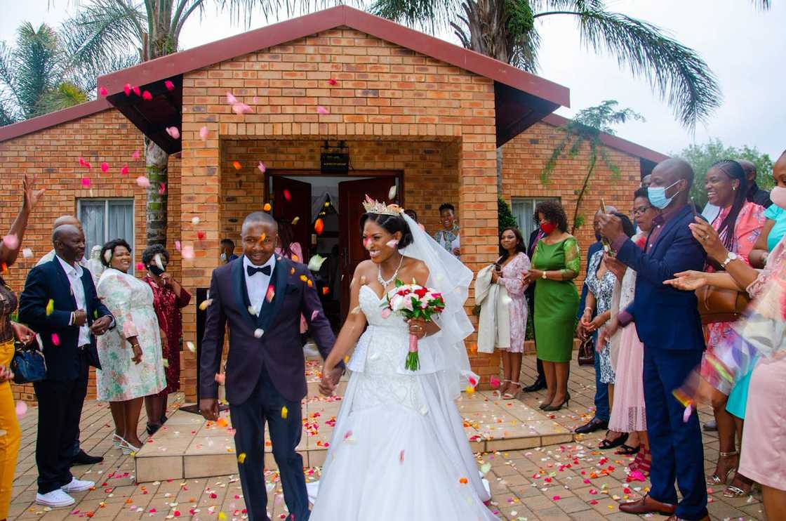 A bride and a groom walk out of a church as guests throw flower petals. A bride and a groom walk out of a church as guests throw flower petals.