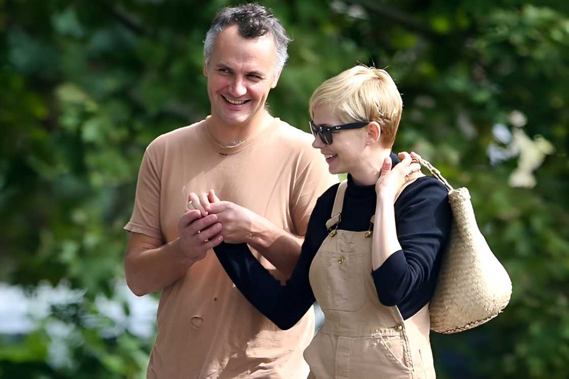 Michelle Williams and Phil Elverum hold hands while on a walk