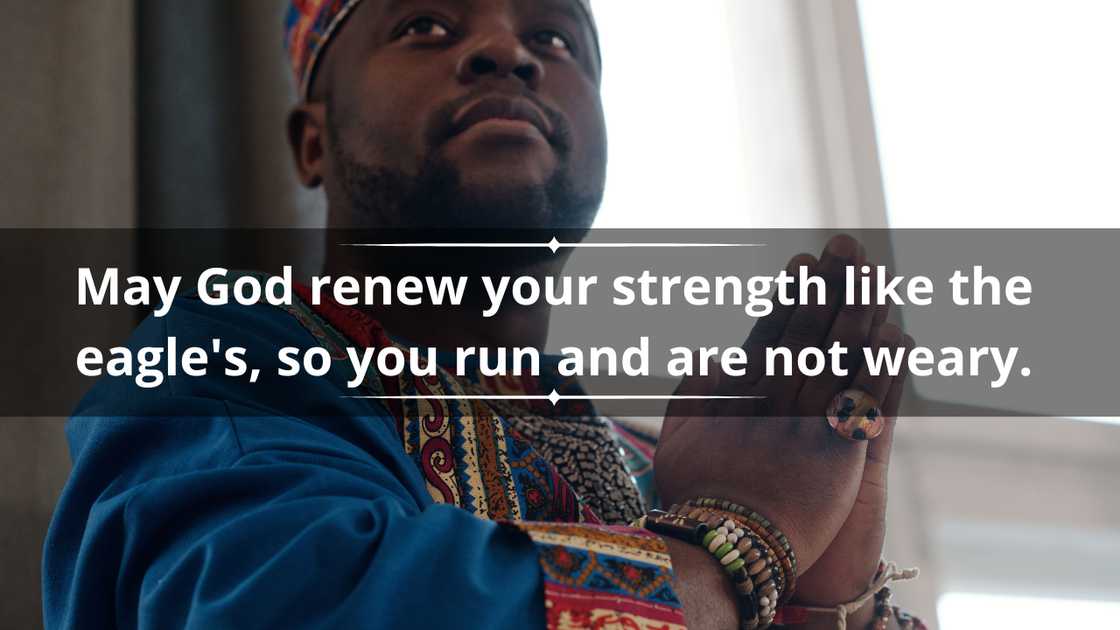 A man in a colourful African outfit holds his hands in prayer
