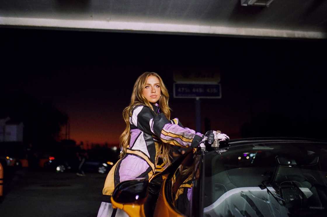 Tate McRae poses leaning against a car