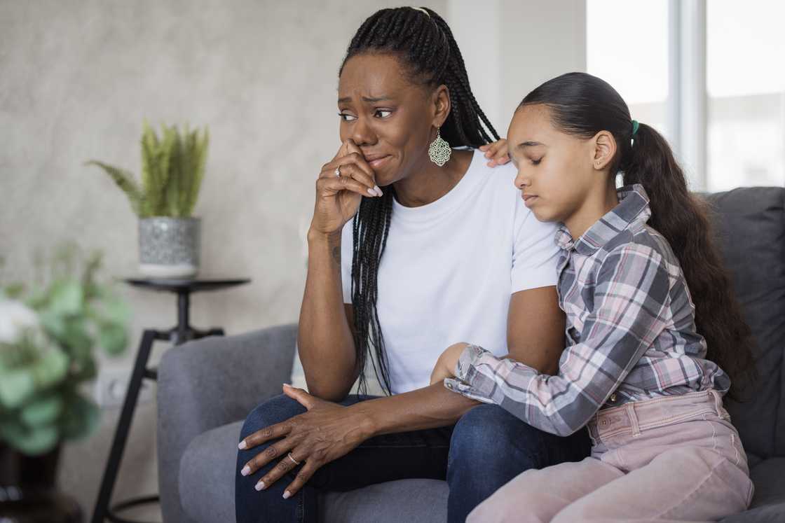 A worried young woman with a frightened child clinging to her shoulders A worried young woman with a frightened child clinging to her shoulders