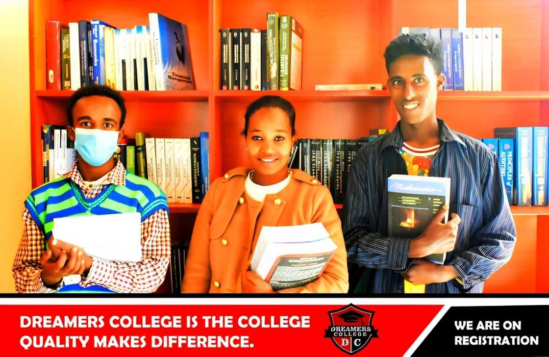 Three Dreamers College students holding books in a library Three Dreamers College students holding books in a library