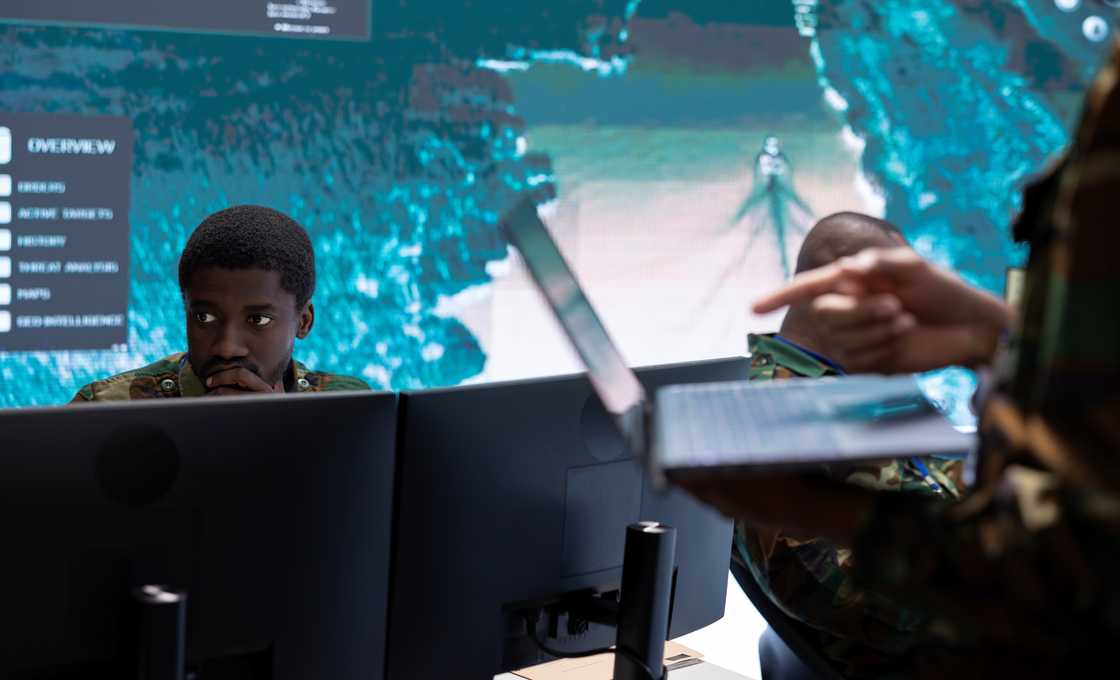 University students sit in a cybersecurity lab while analysing and monitoring real-time data on monitors. University students sit in a cybersecurity lab while analysing and monitoring real-time data on monitors.