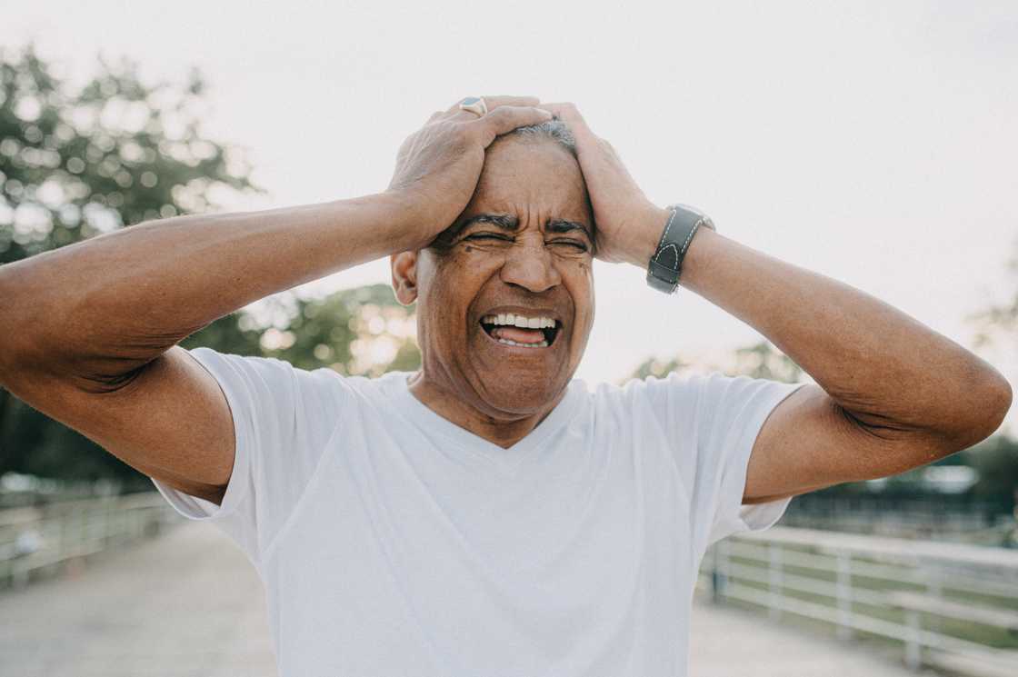 A stressed man holds his head in anger