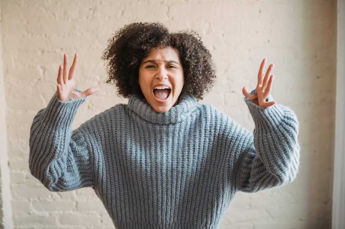 A woman raises her hands and shouts in frustration. A woman raises her hands and shouts in frustration.