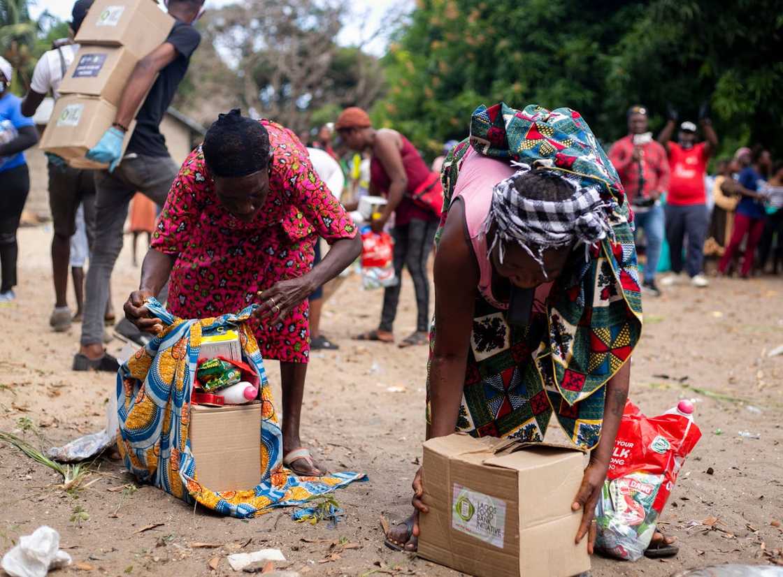Women bend to collect relief supplies from cardboard boxes. Women bend to collect relief supplies from cardboard boxes.