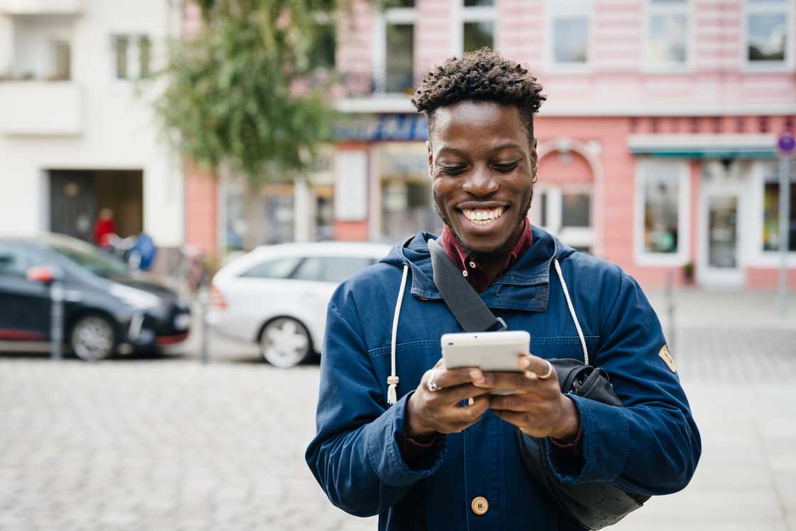 A young man smiling while using a phone