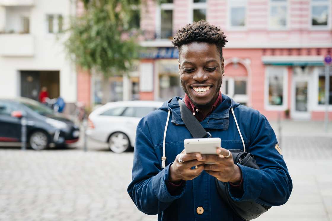 A young man smiling while using a phone A young man smiling while using a phone