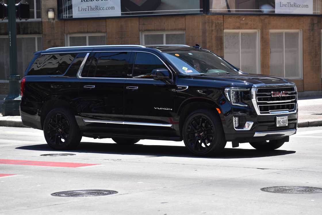 A portrait of a black GMC Yukon XL cruising in a downtown financial district. A portrait of a black GMC Yukon XL cruising in a downtown financial district.