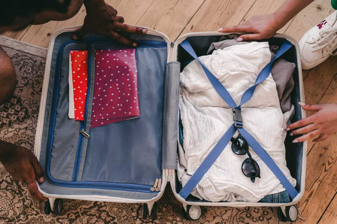 Hands pack clothes and accessories into an open suitcase. Hands pack clothes and accessories into an open suitcase.