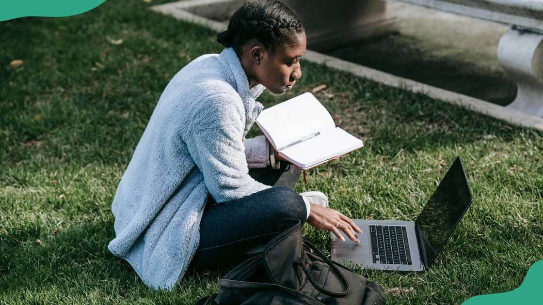 A student sits on a grass lawn as she studies A student sits on a grass lawn as she studies