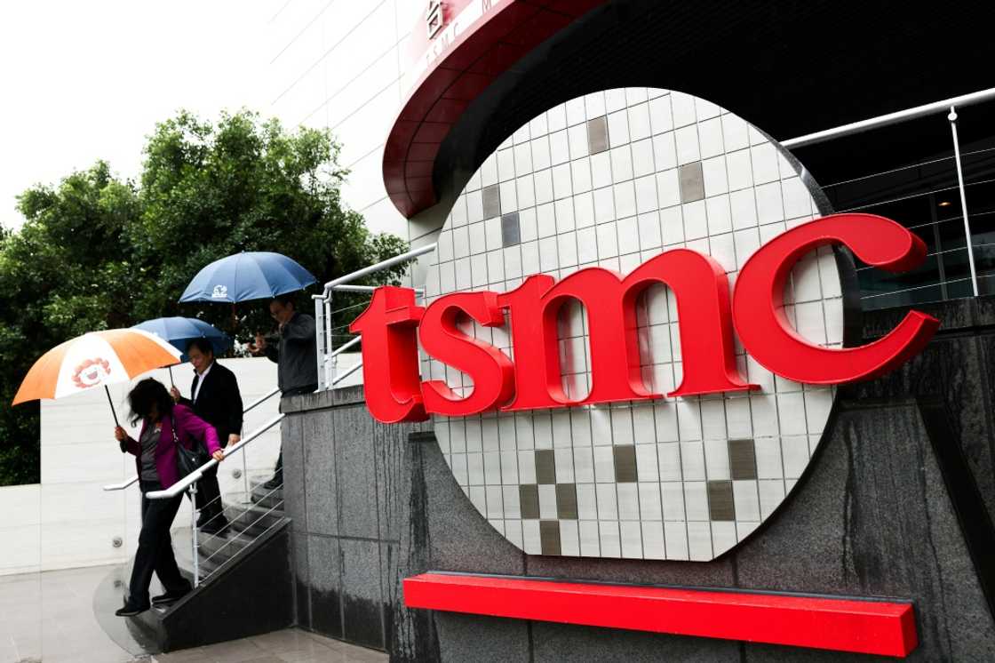 People walk beside Taiwan Semiconductor Manufacturing Company (TSMC) signage in Hsinchu