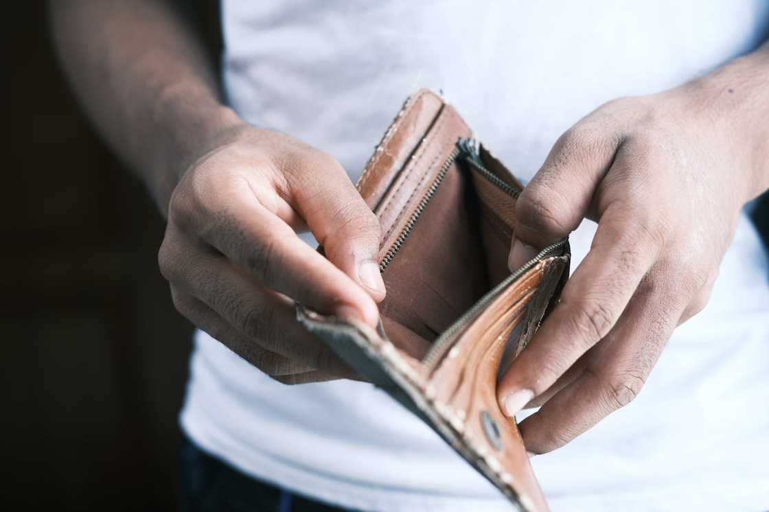 A person holds an empty wallet open with both hands.