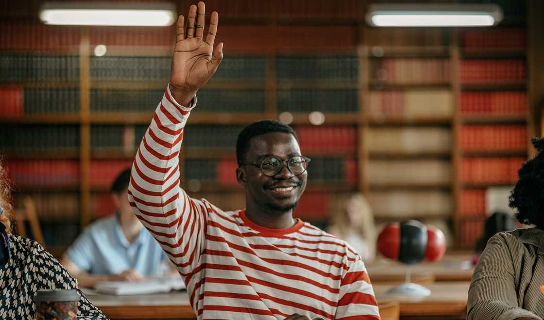A university student raises his hand during a lecture. A university student raises his hand during a lecture.