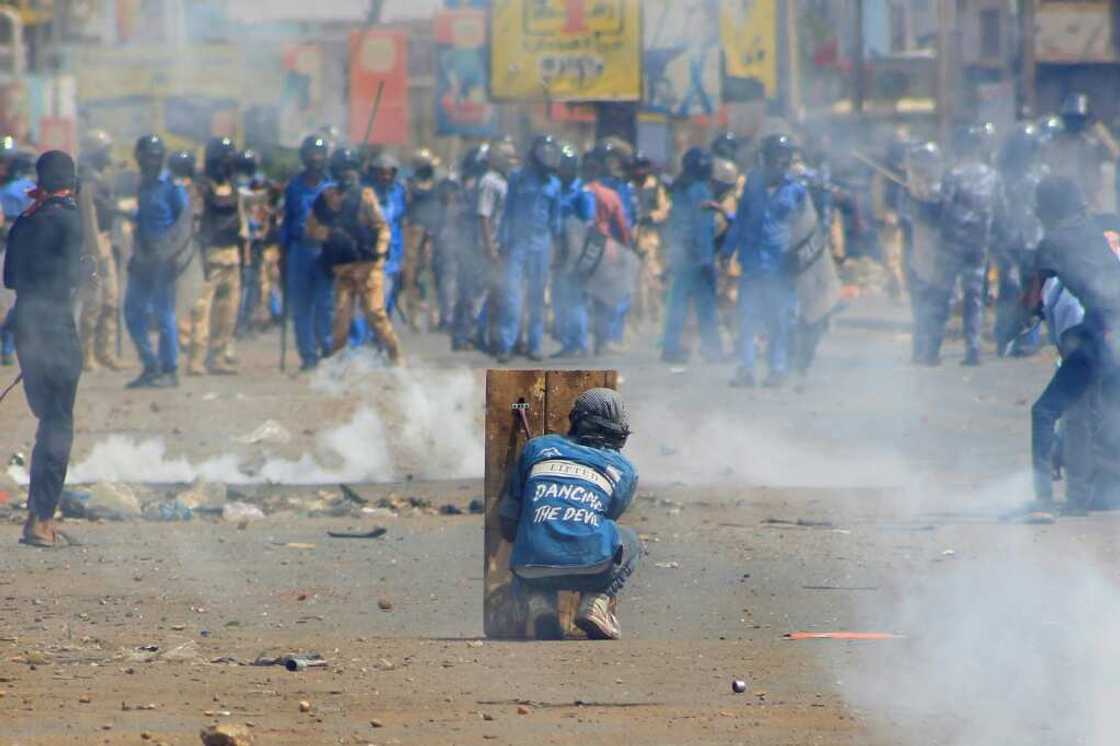 A Sudanese protester takes cover on Thursday from tear gas fired by security forces amid clashes in the Khartoum Bahri twin city of the Sudanese capital