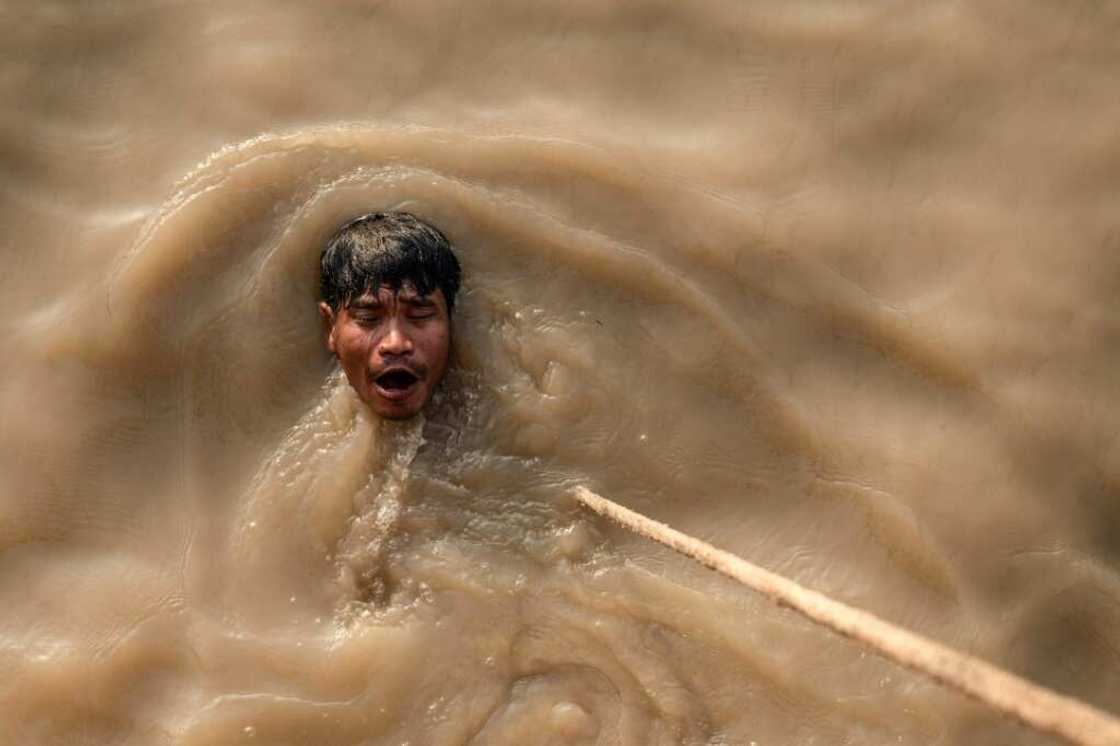 A man swims after a dive to recover a sunken ship in the Yangon River; scrap dealers buy the metal and melt it down to be used again