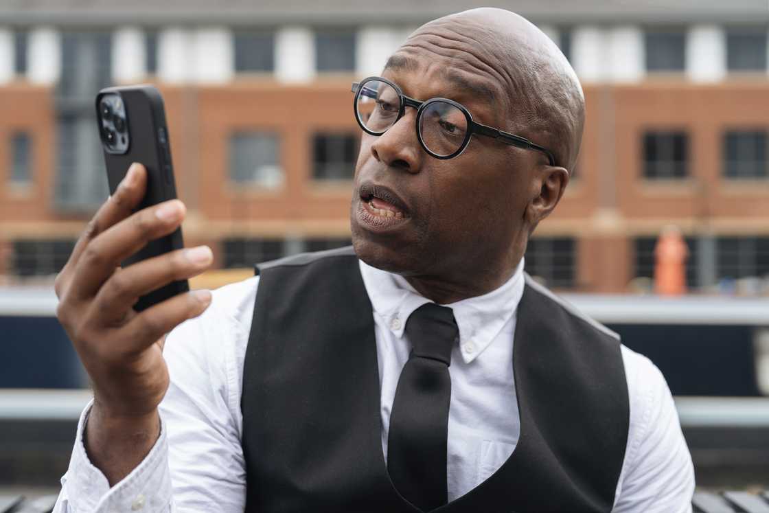 A man in disbelief after seeing a CCTV footage in a phone A man in disbelief after seeing a CCTV footage in a phone