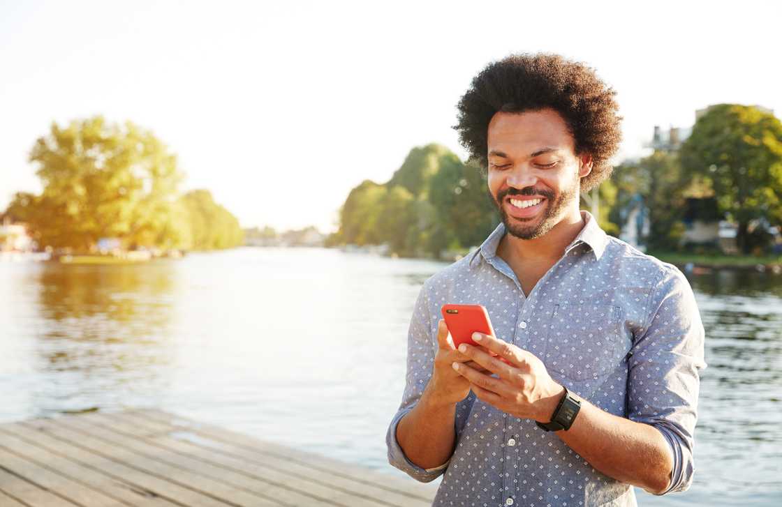 A man using smartphone next to river A man using smartphone next to river