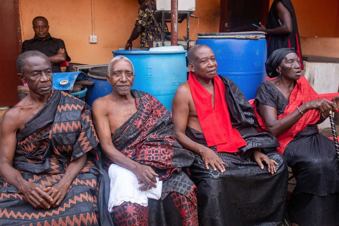 Elderly men and woman seated together in traditional attire.