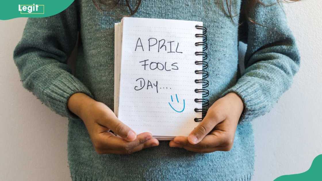 Little girl holding a notebook written Aprils Fool Day