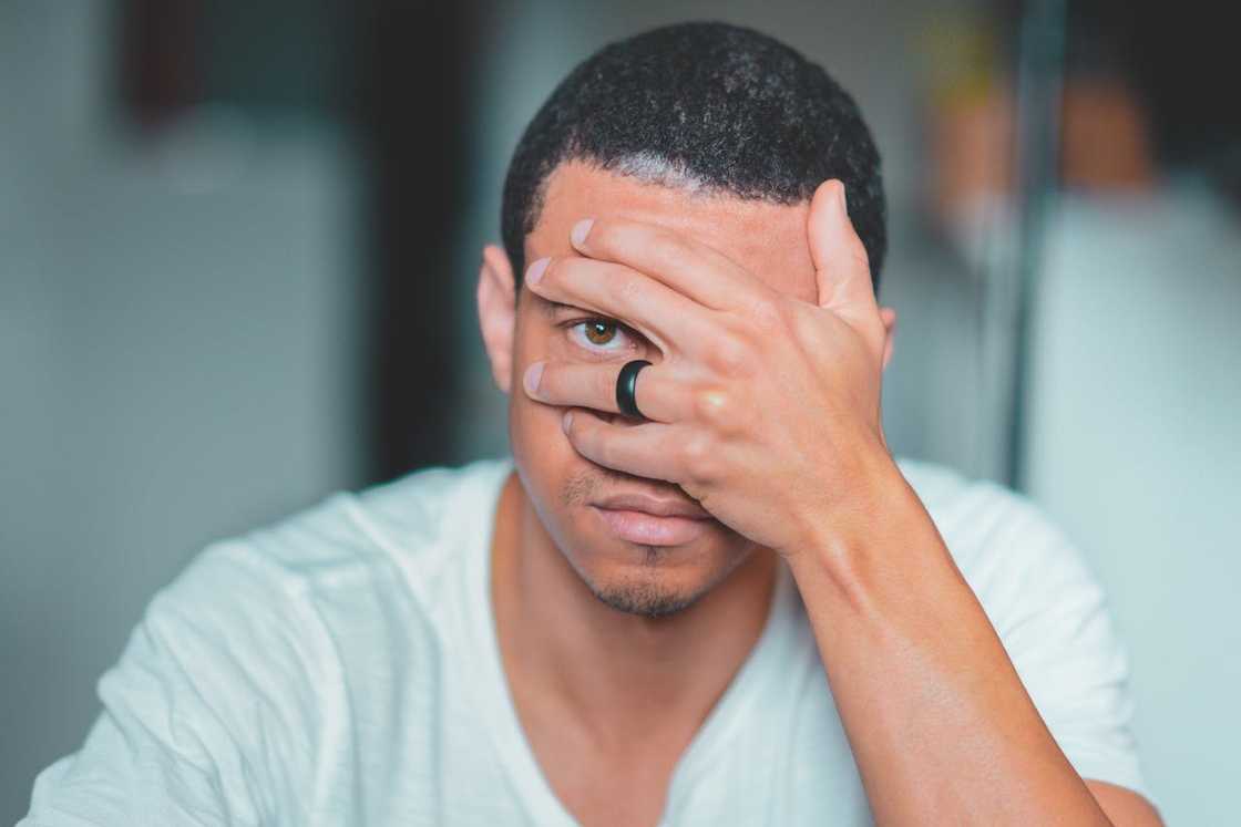 A man covers part of his face with his hand, looking stressed.