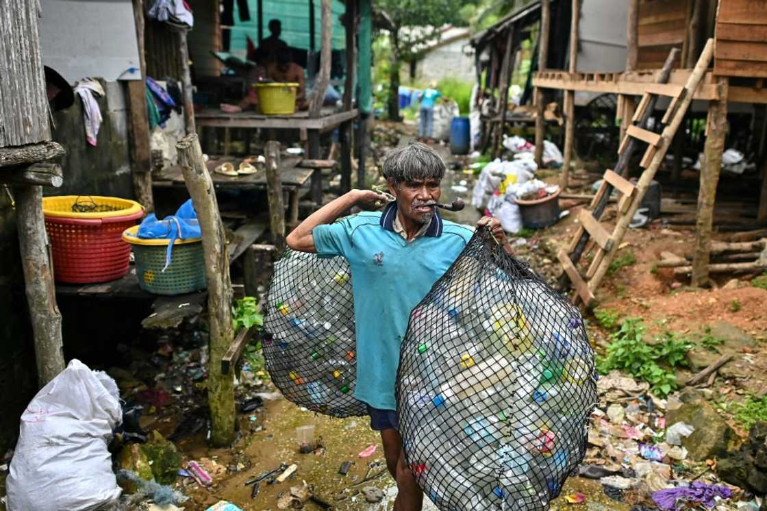 A fisherman at his village on Thailand's southern island of Koh Chang carries bags of plastic waste to sell