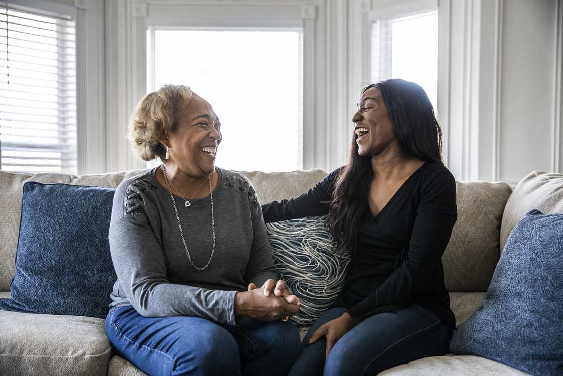 A senior mother talking with adult daughter on sofa
