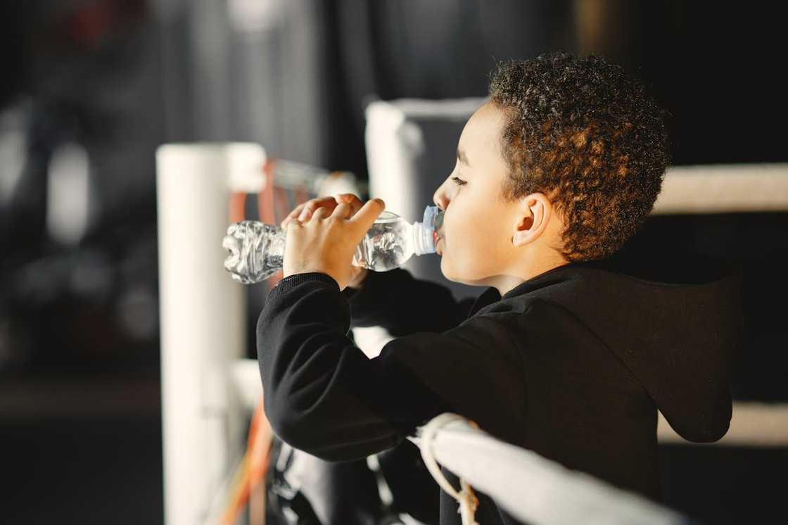 Boy drinking water from a plastic bottle.