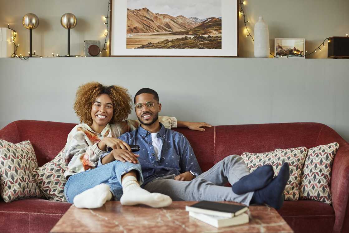 Portrait of smiling Afro woman watching TV with boyfriend