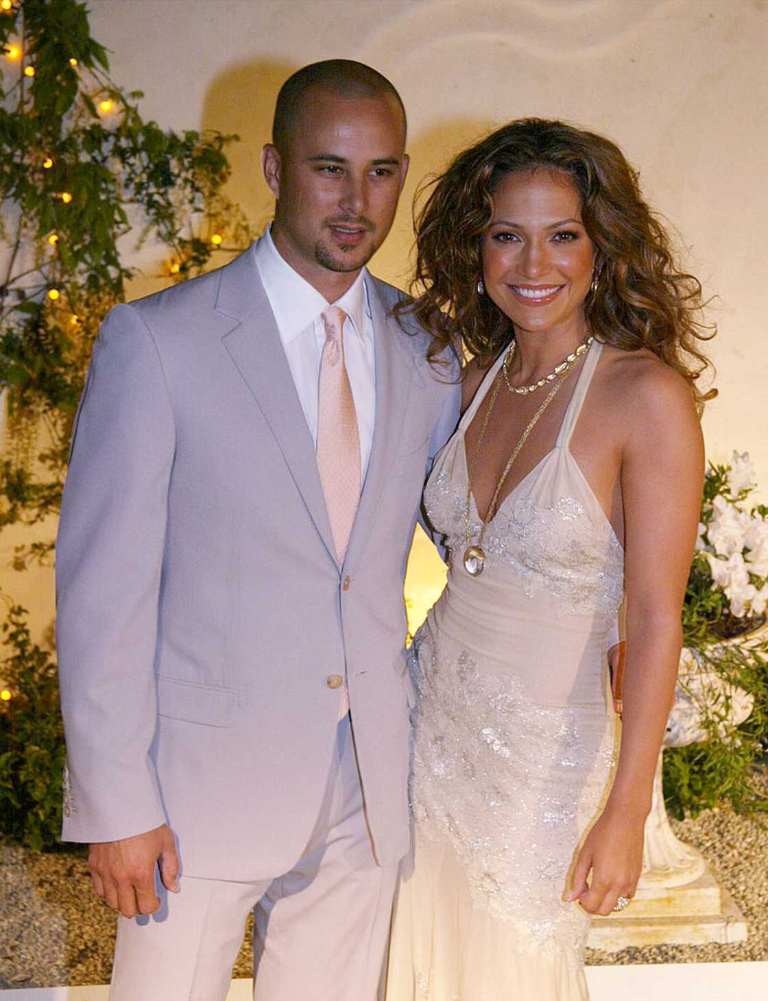 Jennifer Lopez in a cream beaded gown beside a man in a light grey suit. Jennifer Lopez in a cream beaded gown beside a man in a light grey suit.