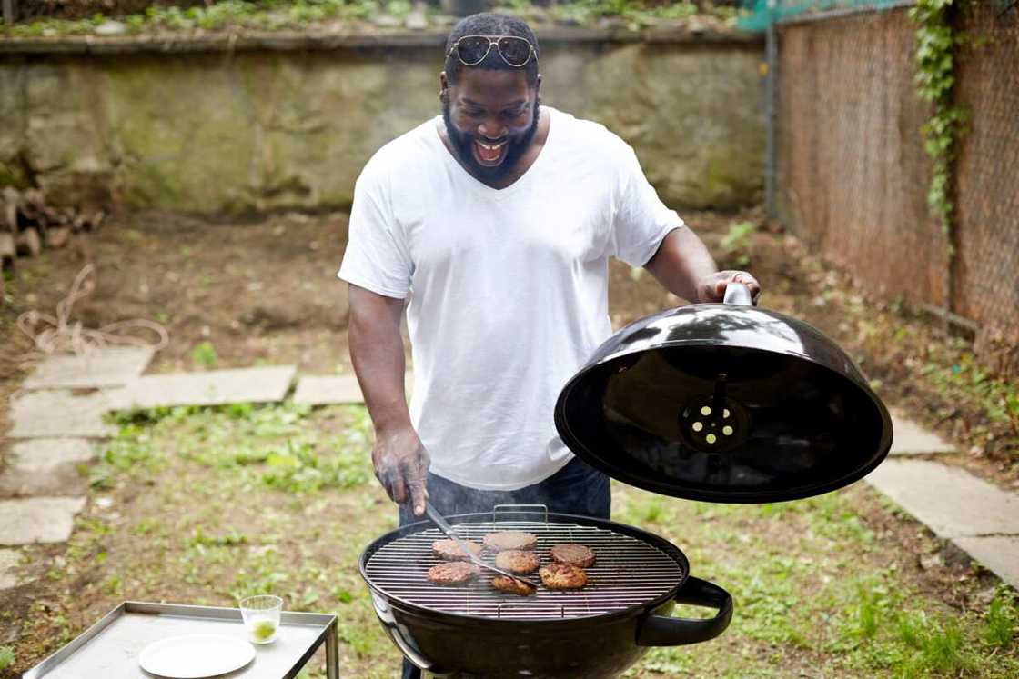 Black man grilling hamburgers at backyard barbecue