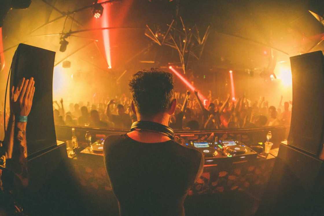 A DJ in a room full of people partying to disco music A DJ in a room full of people partying to disco music