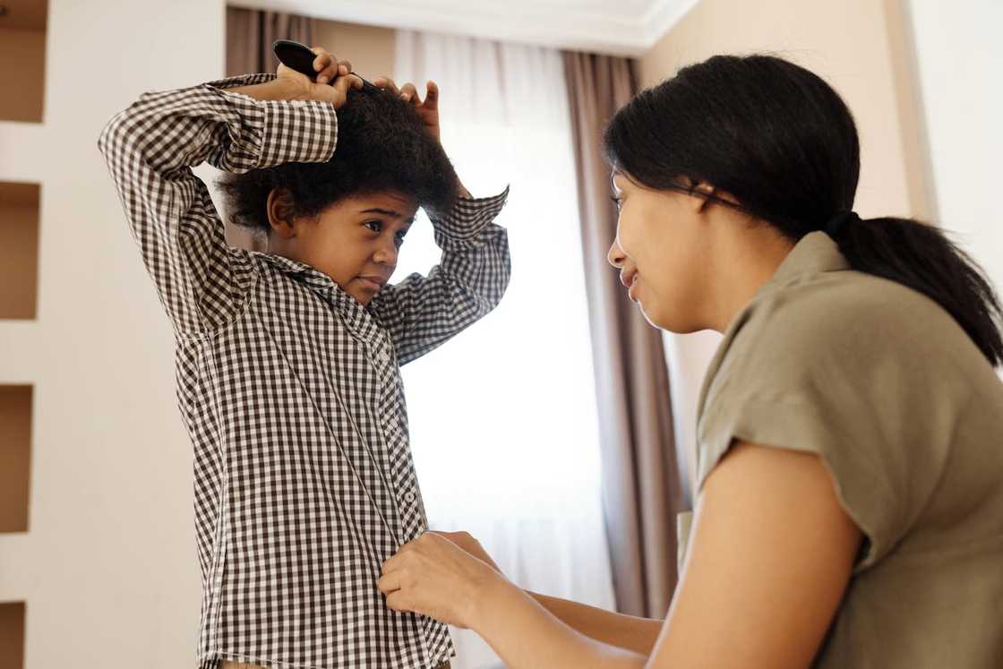 A mother helping a young boy comb his hair at home. A mother helping a young boy comb his hair at home.