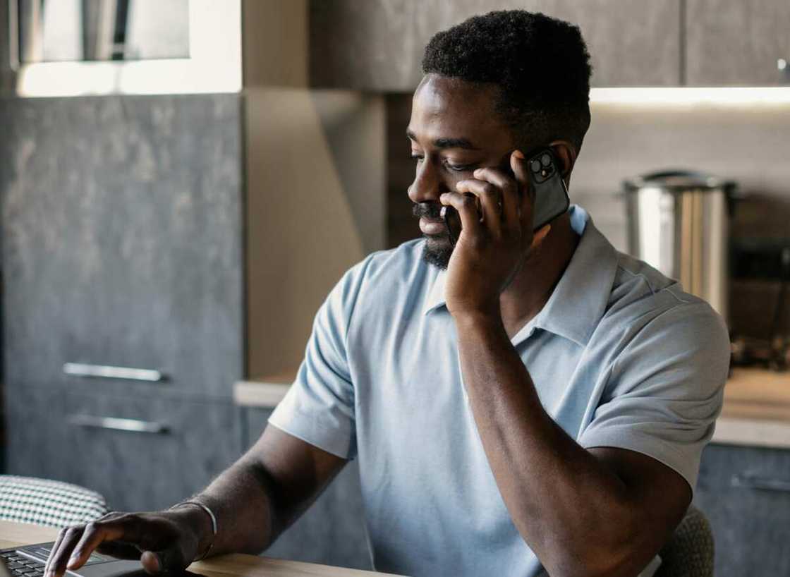 A young man on phone while using a laptop A young man on phone while using a laptop
